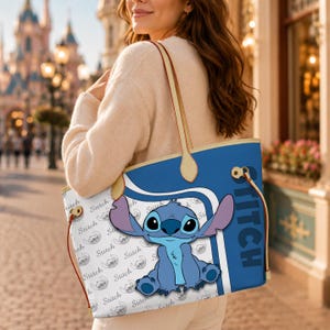 Puede incluir: Un bolso tote azul y blanco con el personaje Stitch de la pel&iacute;cula de Disney Lilo & Stitch. El bolso tiene un fondo azul con la palabra "STITCH" impresa verticalmente. El cuerpo principal del bolso tiene un fondo blanco con un patr&oacute;n repetido de Stitch.