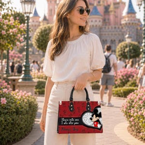 May include: A red rectangular handbag featuring a repeating Mickey Mouse pattern, a large heart-shaped graphic with Mickey Mouse, and the text "Touch this and I will bite you" followed by "Nancy's Bag" in black script on the front panel.