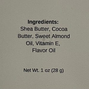 May include: A white ceramic mug with a black handle and the text "But First, Coffee" in a bold, black font. The mug is filled with a dark liquid, likely coffee, and sits on a light-colored surface.