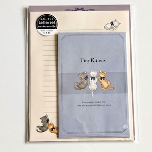 May include: A stationery letter set featuring a light blue envelope with three kittens wearing black bows and the text Tiny Kittens. The set includes cream-colored lined writing paper with kitten illustrations and a circular label indicating 4 envelopes and 8 sheets.