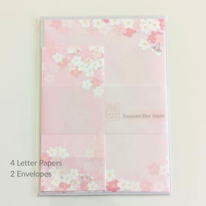Könnte beinhalten: Ein Schreibwarenset mit rosa Briefpapier und Umschlägen, verziert mit weißen und rosa Kirschblütenmustern. Das Set enthält 4 Briefbögen und 2 Umschläge, bedruckt mit einem kleinen Geschenkbox-Symbol und dem Text Treasure Box Japan.