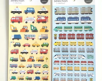 Puede incluir: Dos hojas de pegatinas verticales etiquetadas como Sticker Selection y Made in Japan. La hoja izquierda tiene un fondo amarillo con varias ilustraciones coloridas de vehículos de emergencia, maquinaria de construcción y coches. La hoja derecha tiene un fondo azul claro con filas de varias ilustraciones de trenes y vagones.