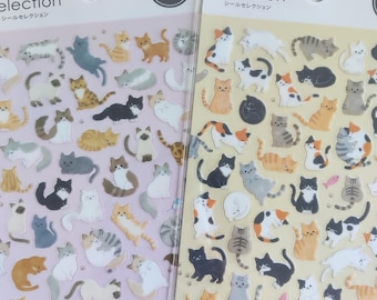 Puede incluir: Dos hojas de pegatinas de gatos etiquetadas como Sticker Selection y Made in Japan. La hoja izquierda tiene un fondo morado claro y la derecha un fondo amarillo claro. Ambas hojas presentan numerosas ilustraciones pequeñas y variadas de gatos.