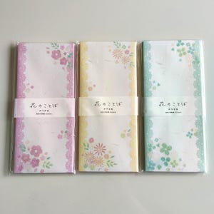 May include: Three rectangular packs of stationery paper in pink, yellow, and green. Each pack features a lace-like border, floral illustrations, and a white paper band printed with the Japanese text 花のことば, 伊予和紙, and 長形4号封筒 8 sheets.