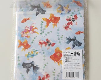 Puede incluir: Un juego de papelería en una funda de plástico transparente con un estampado de acuarela de peces dorados naranjas, negros y blancos nadando entre plantas acuáticas verdes sobre un fondo azul claro. Incluye una etiqueta blanca con texto.