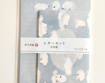 Puede incluir: Un juego de papelería en una funda de plástico transparente con fondo azul claro, osos polares blancos, nubes y estrellas. Una banda de papel blanca en el centro muestra el texto japonés "レターセット", "日本製", "伊予和紙" con iconos de tres sobres y seis hojas de papel.