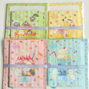 以下が含まれることがあります： Sweets animalsという文字が書かれた4種類のレターセット。それぞれ異なるパステルカラーのストライプ背景で、フルーツパフェやソーダなどのデザートと小さな動物たちが描かれたイラストがデザインされています。