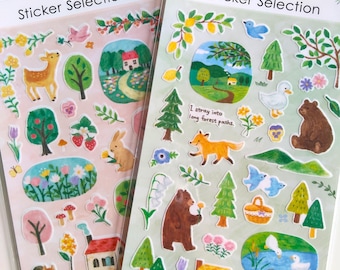 Puede incluir: Dos hojas de pegatinas decorativas con ilustraciones estilo acuarela de animales del bosque, árboles, flores y casas. La hoja izquierda tiene un fondo rosa, mientras que la derecha es verde claro e incluye el texto "I stray into long forest paths" y "It's a quiet lakeside. Take a break."