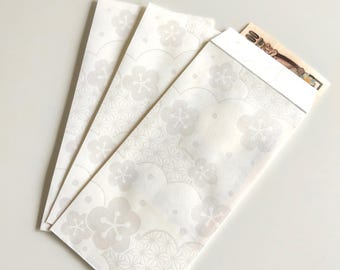 May include: Three rectangular white paper envelopes featuring a subtle, light grey pattern of plum blossoms and geometric hemp leaf designs. One envelope is partially open, revealing a portion of a Japanese banknote tucked inside the top edge.