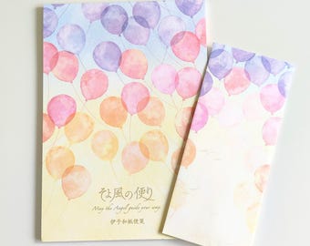 Puede incluir: Una hoja de papel de carta rectangular y un sobre a juego con una ilustración en acuarela de globos morados, rosas y naranjas sobre un fondo degradado. El texto dice: そよ風の便り, May the Angel guide your way, e 伊予和紙便箋.