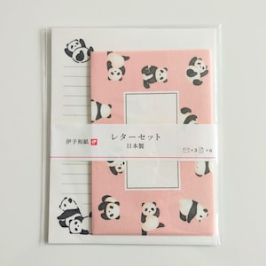 Op de afbeelding: Een briefpapier set met een wit gelinieerd papierblok met zwarte panda-illustraties en een roze envelopset met panda-afbeeldingen. Een papieren band in het midden toont de Japanse tekst "レターセット" en "日本製" met iconen voor drie enveloppen en zes vellen.