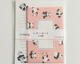 Puede incluir: Un juego de papelería que incluye un bloc de papel blanco con líneas e ilustraciones de pandas negros, y un paquete de sobres rosas con gráficos de pandas. Una banda central muestra el texto japonés "レターセット" y "日本製" con iconos de tres sobres y seis hojas.