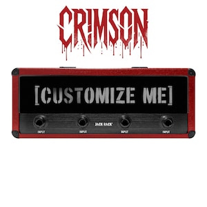 May include: A red and black audio device with the word "CRIMSON" in a dripping font above. The device has the text "[CUSTOMIZE ME]" and "JACK RACK" printed on it, along with four input jacks.