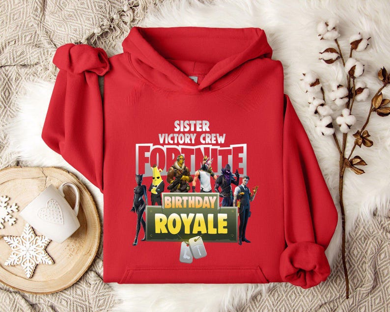 Pu&ograve; includere: Una felpa con cappuccio rossa con la scritta "SISTER VICTORY CREW FORTNITE BIRTHDAY ROYALE" e grafica di personaggi. La felpa ha una tasca a marsupio e un cappuccio con coulisse. Il design presenta personaggi del videogioco Fortnite.