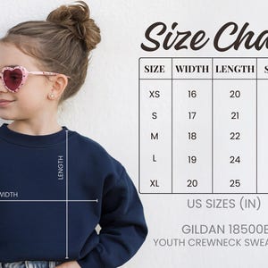 A young girl wearing a navy blue crew neck sweatshirt and pink heart-shaped sunglasses, with a size chart and US sizes (IN) for the sweatshirt.