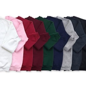 A row of colorful long-sleeved shirts in various colors, including white, pink, red, green, blue, and gray.