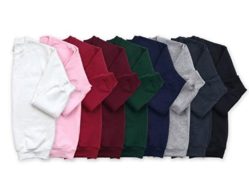 A row of colorful long-sleeved shirts in various colors, including white, pink, red, green, blue, and gray.