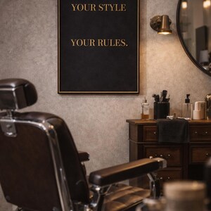 Peut inclure: Un panneau noir encadré avec des lettres dorées qui dit "YOUR STYLE YOUR RULES". Le panneau est accroché sur un mur gris texturé au-dessus d'un fauteuil de barbier. Une petite lampe et un miroir rond sont également visibles.