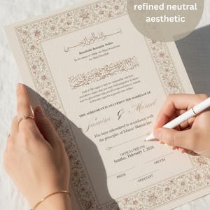 Peut inclure: Un certificat de mariage beige avec des bordures florales ornées et de la calligraphie arabe. Le document est signé avec un stylo blanc. Le texte sur le certificat se lit "THIS AGREEMENT IS TO CERTIFY THE MARRIAGE OF Samira & Murad".