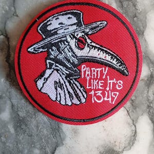 Peut inclure: Un écusson rond rouge avec une bordure noire présente une illustration détaillée d'un médecin de la peste en blanc et noir. Le texte "PARTY LIKE IT'S 1349" est brodé en blanc. Cet écusson convient aux vestes, sacs ou autres articles en tissu.