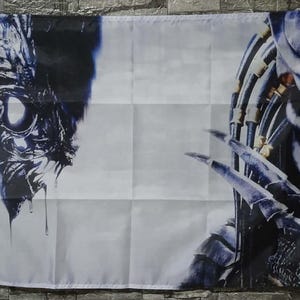 May include: A white flag featuring a detailed, artistic depiction of a Predator creature. The design is split, with a close-up of the creature's face on the left and its claws on the right. The artwork is primarily in shades of blue and black.