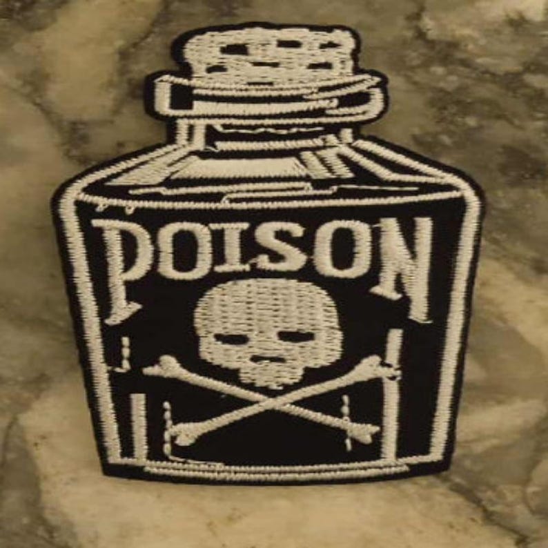 Peut inclure: &Eacute;cusson brod&eacute; noir et blanc en forme de flacon de poison. Le mot "POISON" est affich&eacute; en blanc, au-dessus d'un cr&acirc;ne et d'os crois&eacute;s. L'&eacute;cusson a une bordure blanche.