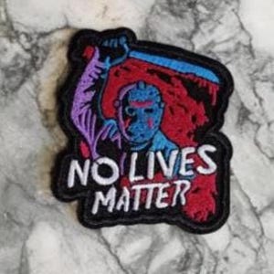 Puede incluir: Un parche negro con un personaje de película de terror con una máscara azul y un machete levantado. El fondo es rojo y negro, con el texto "NO LIVES MATTER" en blanco.