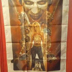 May include: A rectangular flag featuring a movie poster for the film "31" by Rob Zombie. The poster has a brown and beige color scheme, with images of characters and the film's title at the bottom.
