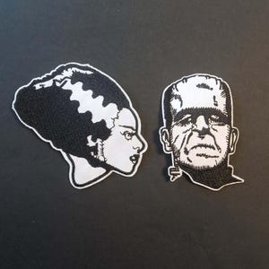 Peut inclure: Deux écussons brodés représentant des personnages de films d'horreur classiques. L'un représente la fiancée de Frankenstein de profil, l'autre le monstre de Frankenstein. Les deux écussons sont en noir et blanc.