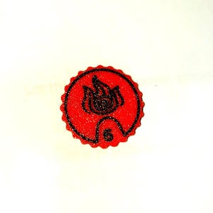 May include: A round, red emblem with a black outline and a scalloped edge. The emblem features a stylized flame design and the number 6. The design is centered on a white background.