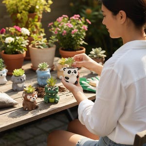 May include: A selection of small, animal-shaped ceramic plant pots, each containing a succulent plant. The pots are designed as a panda, bear, crocodile, and other animals. The image shows a person holding a panda pot, with other pots and potted plants in the background.