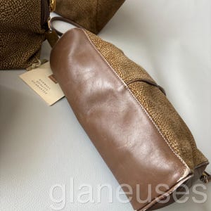 May include: Brown leather handbag with a textured, spotted pattern on the sides and a smooth, solid brown leather body. The bag has a handle and a tag that reads "Redwall Quality Guarantee".