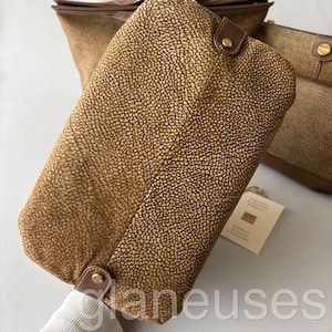 May include: A collection of brown leather handbags with a textured, spotted pattern. The bags have brown leather trim and gold-colored hardware. One bag is in the foreground, with others visible in the background.