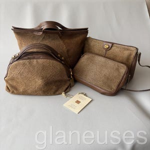 May include: A collection of brown leather handbags and purses. The bags vary in size and style, including a tote, a satchel, and a crossbody bag. The leather has a textured appearance. A tag is attached to one of the bags.