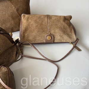 May include: A collection of brown leather handbags with a textured finish. The bags vary in size and style, including a clutch with a gold-tone clasp and a crossbody bag with a thin strap. The bags are displayed on a light gray surface.