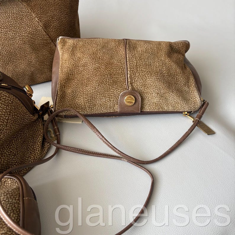 May include: A collection of brown leather handbags with a textured finish. The bags vary in size and style, including a clutch with a gold-tone clasp and a crossbody bag with a thin strap. The bags are displayed on a light gray surface.