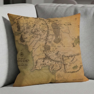 Puede incluir: Cojín cuadrado con un mapa detallado de la Tierra Media, con lugares como Rohan y Mordor. El mapa está impreso en tela color beige, dándole un aspecto vintage. Un artículo decorativo para el hogar.