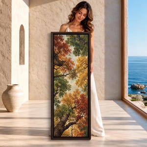 May include: A tall, rectangular framed wall art piece featuring a low-angle view of a forest canopy. The painting displays dense tree branches with autumn foliage in shades of vibrant orange, deep red, golden yellow, and forest green against a pale sky.