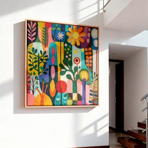 May include: A square canvas painting in a light wood frame featuring a vibrant, abstract botanical composition. The artwork displays stylised flowers, leaves, and geometric shapes in a palette of yellow, orange, pink, green, and blue.