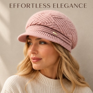 May include: A dusty pink knit newsboy cap featuring a textured chevron pattern, a ribbed brim, and a small metallic oval accent on the side. The text "EFFORTLESS ELEGANCE" is printed in dark brown letters above the cap against a neutral background.