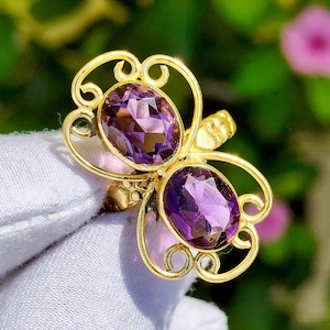 May include: A white ceramic mug with a black handle and the text "But First, Coffee" in a black, handwritten-style font. The mug is on a white surface.