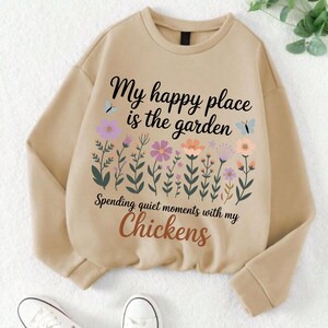 May include: Beige sweatshirt with the text "My happy place is the garden" and "Spending quiet moments with my Chickens." The design includes colorful flowers and butterflies.