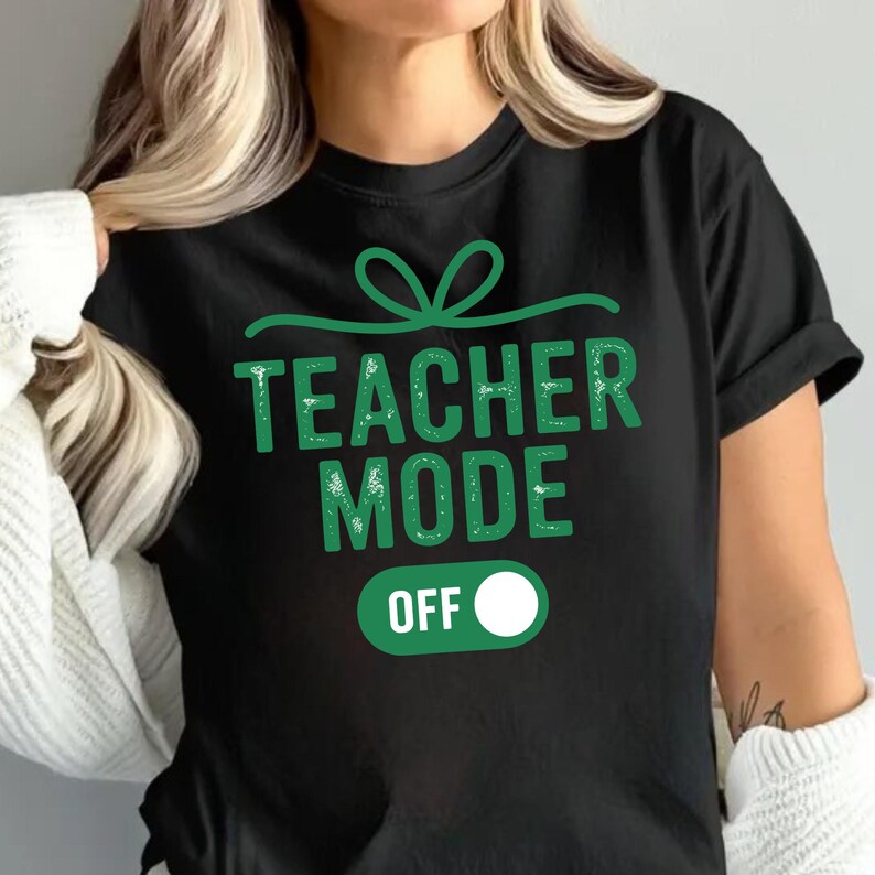 May include: Black t-shirt with the text "TEACHER MODE OFF" in green, featuring a green bow design above the text and an "OFF" switch graphic. The shirt is a casual wear item.