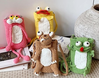 May include: Four handmade crochet crossbody bags in the shape of cartoon animals. The bags are pink, yellow, brown, and green, each with unique facial features and details. The bags have long straps and are displayed on a neutral surface.