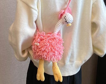 May include: A pink and white crochet flamingo-shaped crossbody bag. The bag features a fluffy pink body, a white head with a pink bow, and yellow feet. The strap is pink, and the bag has a drawstring closure.