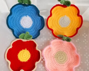 May include: Four handmade crochet flower coasters in blue, yellow, red, and pink. Each coaster has a white or yellow center and green leaf accents. The coasters are designed with a scalloped edge.