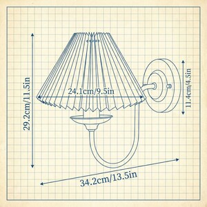 May include: A wall-mounted lamp with a pleated lampshade. The lamp's dimensions are 29.2cm/11.5in high, 24.1cm/9.5in wide, and 34.2cm/13.5in long. The lamp has a circular wall mount and a curved arm supporting the shade. The design is illustrated on a grid background.