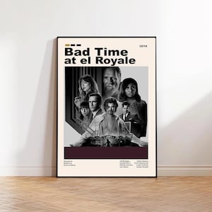 May include: A framed movie poster for "Bad Time at El Royale" featuring a cast of characters in black and white. The title is in bold, dark yellow letters. The poster has a cream background with a dark red stripe at the bottom.