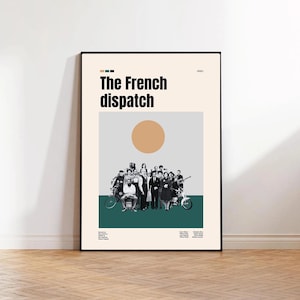May include: A framed poster for "The French Dispatch" movie. The poster features a group of people in black and white, a large orange circle, and the title in bold black letters. The background is a mix of light beige, gray, and teal.