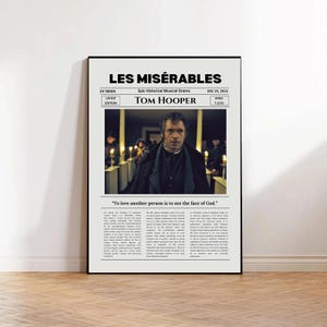 May include: A vertical poster featuring the Les Misérables movie title, director Tom Hooper, and a central photograph of a man in a dark coat. The text includes the quote, "To love another person is to see the face of God," and detailed columns of small printed text.